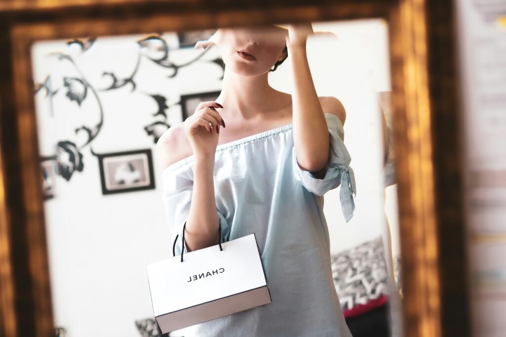 Woman holding a Chanel shopping bag in front of a mirror, representing the allure of luxury in The Psychology of Luxury: Why We Crave High-End Products.